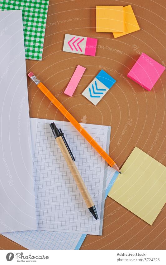 Organisierte Büromaterialien auf einem braunen Hintergrund Vorrat Klebrig Hinweis Bleistift Grafische Darstellung Papier organisiert Arbeitsbereich Overhead