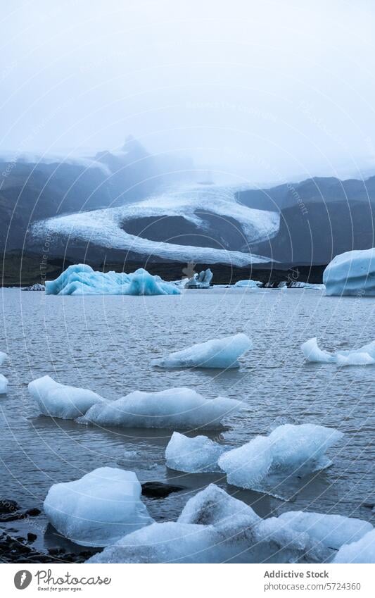 Stimmungsvolles Ambiente mit Eisbergen, die in einer Gletscherlagune schwimmen, vor dem Hintergrund des majestätischen Gletschers des Vatnajökull-Nationalparks in Island