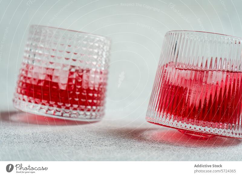 Kirsch-Wodka-Tonic-Cocktail in strukturierten Gläsern Glas Kirsche Vodka Eis Getränk trinken Alkohol Erfrischung Mixologie Bar texturiert rot pulsierend