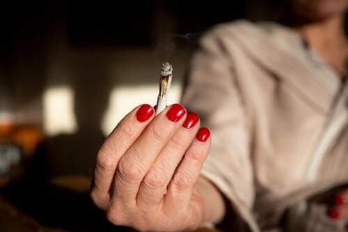 Frau bietet einen Joint an Cannabiskonsum anbieten rauchen Hand Nagellack lackierte fingernägel weiterreichen weitergeben kiffen Rauschmittel Rauchen Frauenhand
