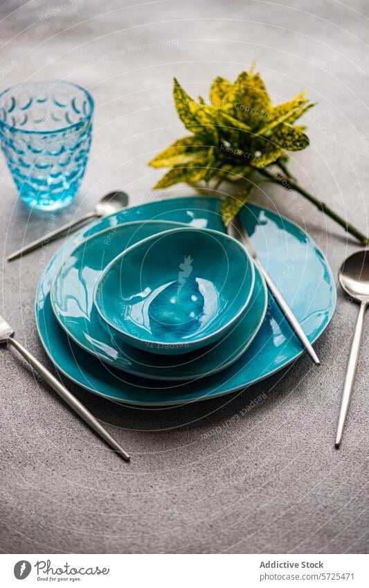 Elegantes türkisfarbenes Geschirrset auf grauem Hintergrund von oben Tisch Einstellung hell Keramik Abendessen Besteck texturiert Oberfläche dekorativ Pflanze