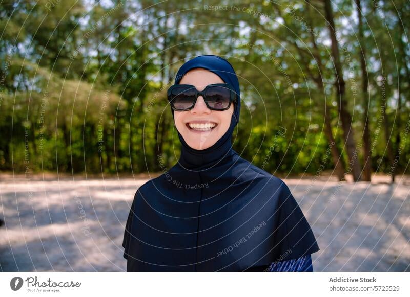 Lächelnde Frau im Burkini genießt den sonnigen Strandtag burkini muslimisch bescheidene Bademode Glück Natur im Freien Hijab Bescheidenheit Komfort Mode Sand