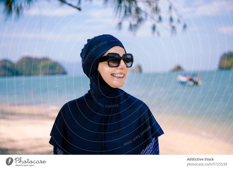 Lächelnde Frau im Burkini genießt die Aussicht auf den Strand burkini MEER Sonnenbrille bescheiden Badebekleidung muslimisch Mode Sand sonnig Insel Ufer