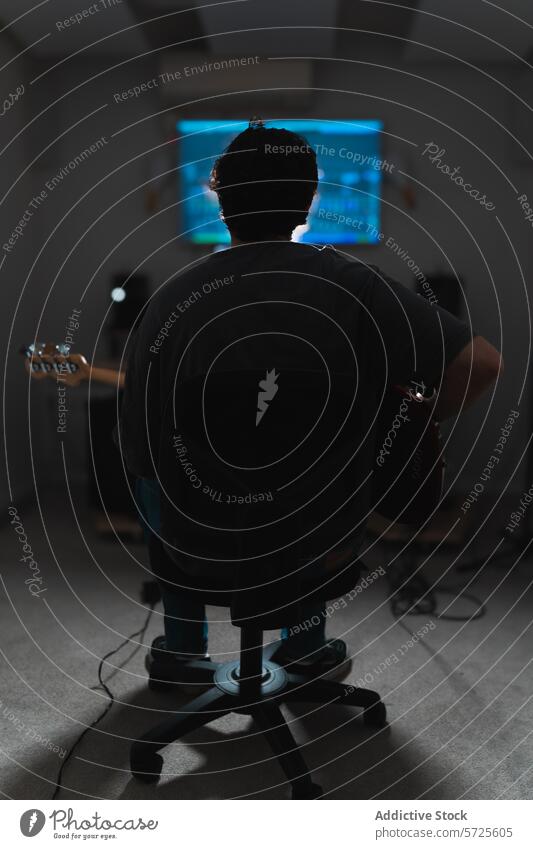 Anonymer männlicher Musiker mit Gitarre während einer Studio-Session Atelier Klang Sitzung Aufnahme Audio Mann Mischen Gerät halbdunkel Licht Sitzen Verkleidung