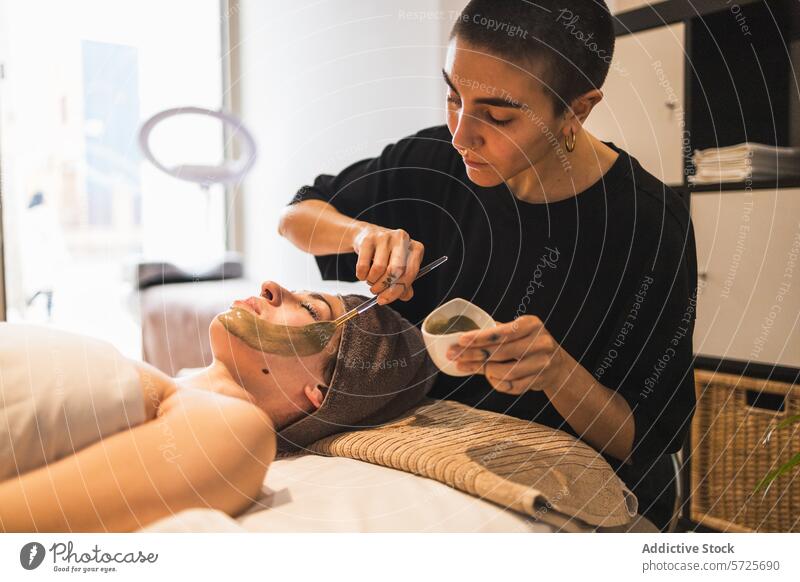 Frau beim Auftragen einer Gesichtsmaske bei einer Schönheitsbehandlung Kosmetikerin Gesichtsbehandlung Mundschutz Behandlung Spa Wellness Hautpflege Erholung