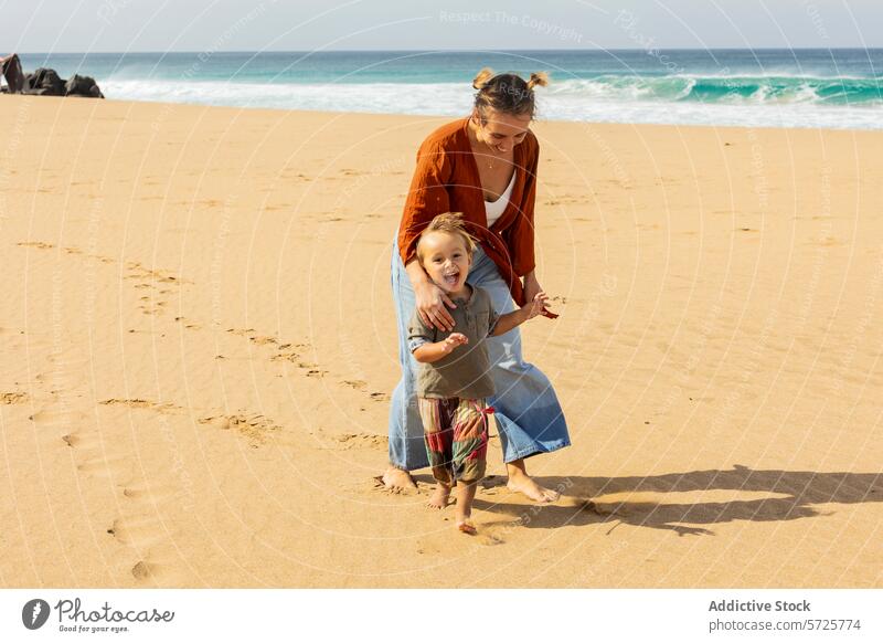 Fröhliche Mutter und Kind spielen am Sandstrand Strand Familie Spaß Meer Junge winken Lächeln Freude sonnig Kindheit sorgenfrei Eltern Seeküste Kleinkind Bonden