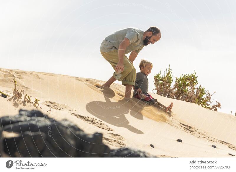 Verspielte Familienmomente auf einer Sanddüne am Strand Düne Vater Kind spielen Freude Sonnenlicht Vegetation Schatten Muster im Freien Sommer Spaß Urlaub