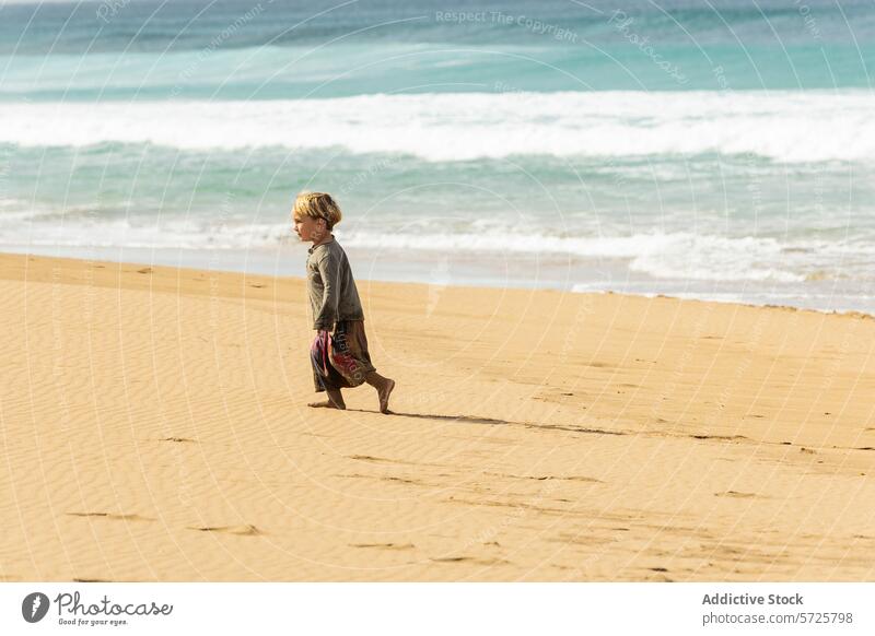 Junge, der allein an einem Sandstrand spazieren geht Kind Strand Meer winken Spaziergang Gelassenheit sonnig Tag nachdenklich Unschuld Erkundung Wasser Seeküste