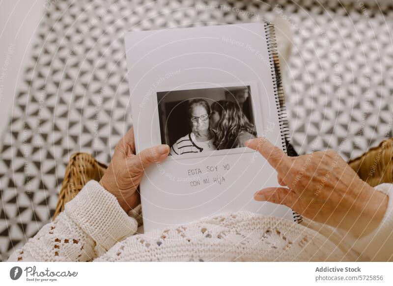 Ältere Frau hält ein Fotoalbum mit einem Familienfoto Senior Album Bild schwarz auf weiß Pullover älter untersuchen Reminiszenz Gedächtnis Moment Beteiligung