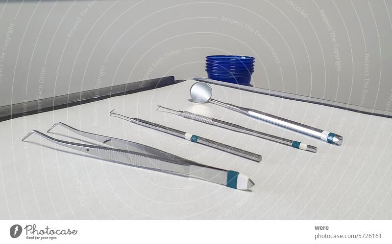 Zahnärztliches Untersuchungsset auf einem Tablett mit weißem Hintergrund und einem Stapel blauer Plastikbecher Zahnarzt antibakteriell Textfreiraum Dentalklinik