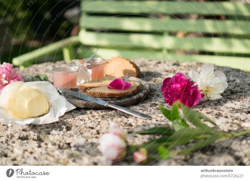 Frühstück im Garten mit selbst gemachter Rosenblütenmarmelade Butter und Brot auf Steintisch garten Pflanze grün Natur Grünpflanze Außenaufnahme natürlich Park