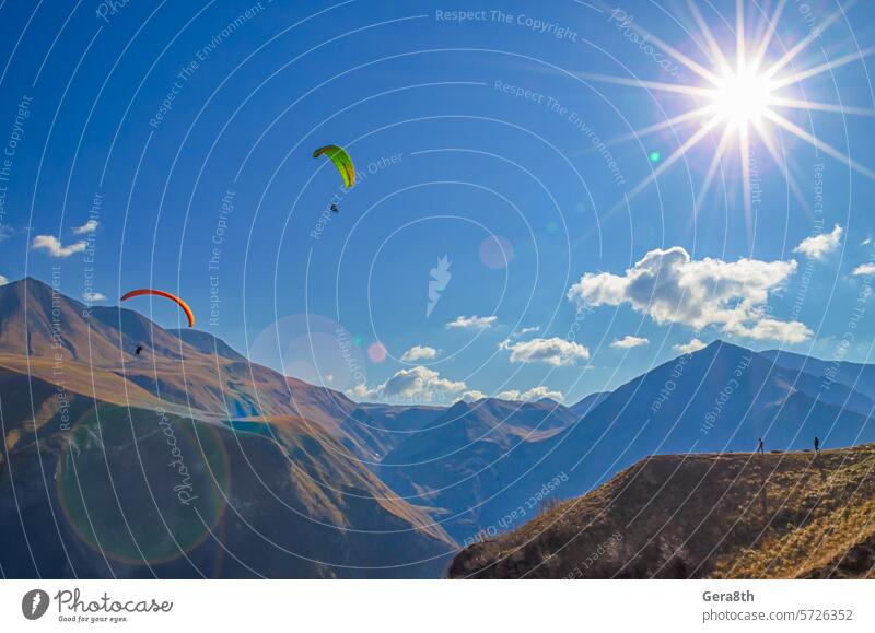 Gleitschirmflieger und Touristen in den Bergen des Kaukasus mit Sonnenfackeln hell Europa extremal Extremsport Fliege fliegen Schlucht Reise Landschaft