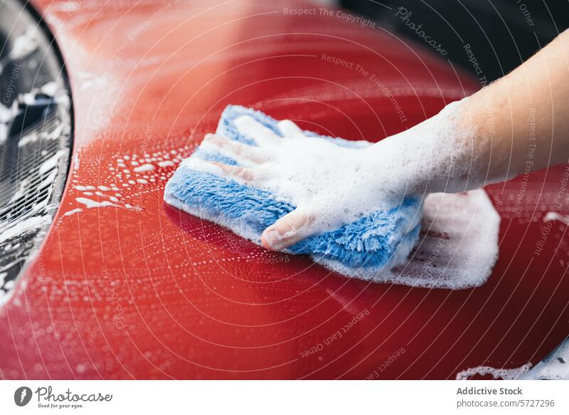 Handwäsche mit Schaum auf einer glänzenden roten Autooberfläche PKW Waschen schäumen blau Mikrofaser Stoff schaumig Oberfläche Reinigen Flugzeugwartung