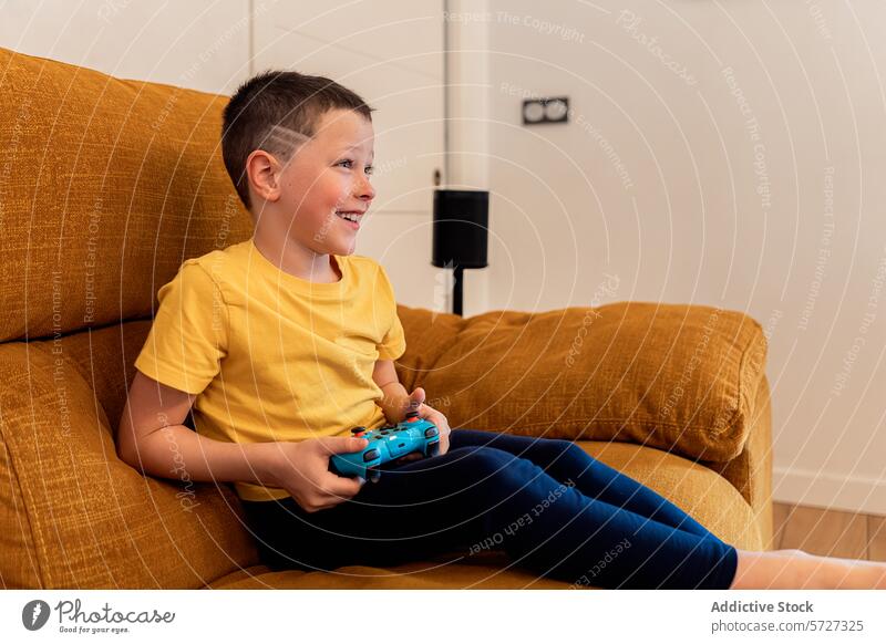 Lächelnder Junge, der auf einem gemütlichen Sofa Videospiele spielt Kind Regler Spielen Spaß Freizeit Aktivität Engagement Genuss jung heimwärts Wohnzimmer