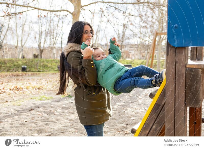 Das Lachen eines Kindes schallt durch den Park, als es in die wartenden Arme seiner Mutter gleitet und beide einen Moment der Freude teilen lachen Spielzeit