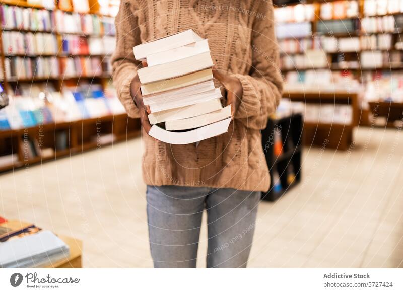 Person mit einem Bücherstapel in einer Bibliothek Buch Stapel Beteiligung Literatur lesen Bildung Wissen Lernen Bücherregal Gang Sammlung Pullover Nahaufnahme