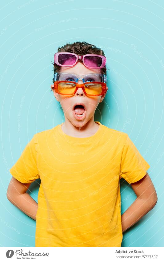 Junge mit mehreren Sonnenbrillen erstaunt spielerisch Ausdruck überrascht pulsierend türkis Hintergrund jung Kind farbenfroh Mode schrullig Spaß Brille heiter