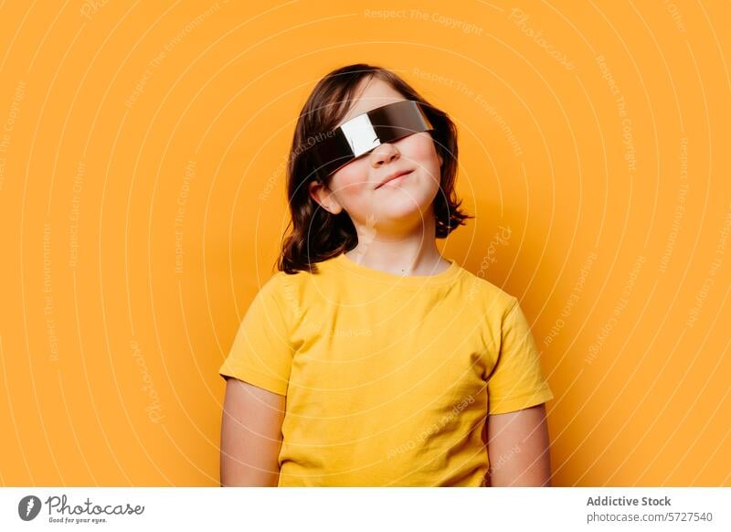 Lächelndes Kind mit futuristischer Sonnenbrille auf orangefarbenem Hintergrund Mädchen strahlend überdimensioniert lebhaft Kinder Glück Freude jugendlich Mode