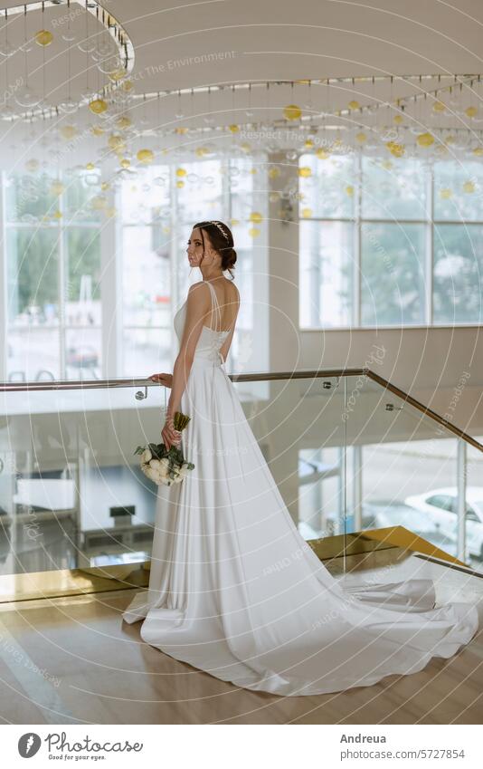Die Braut auf der Treppe des Goldhotels Blumenstrauß braun Tag Kleid erste Mädchen gehen Sie gold Typ Hotel heiraten Sitzung Jungvermählte Lächeln Freitreppe