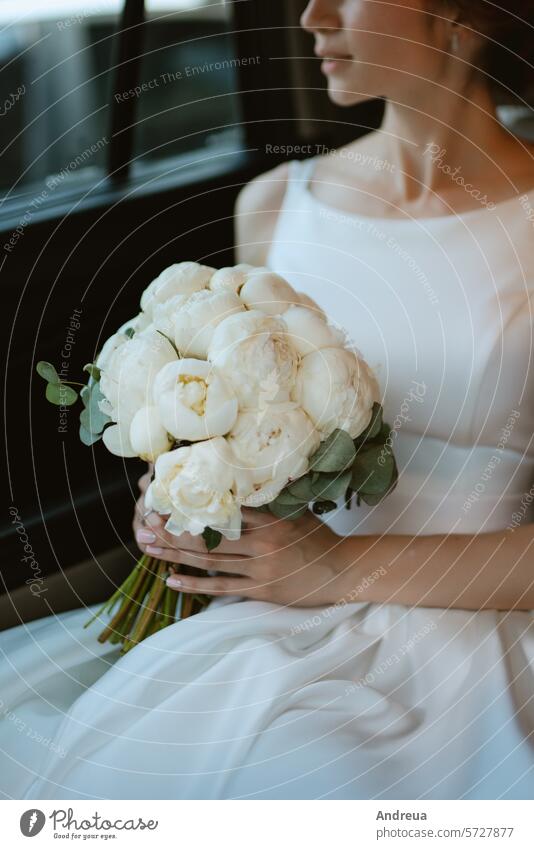 Braut mit schwarzem Auto in der Nähe eines gläsernen Wolkenkratzers PKW nah Glas Hotel Straße weiß grau Asphalt blau Gebäude Hochzeit Blumenstrauß stehen
