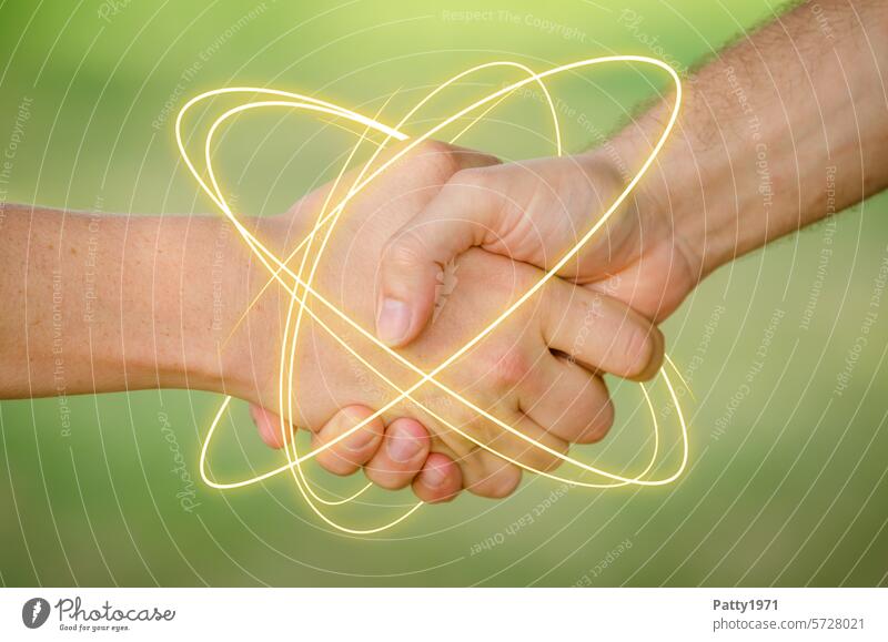 Zwei junge Männer geben sich die Hand. Eine Neon Leuchtspur umkreist die Hände.Nahaufnahme der Hände vor grünem Hintergrund. Haende Handschlag Hände schütteln