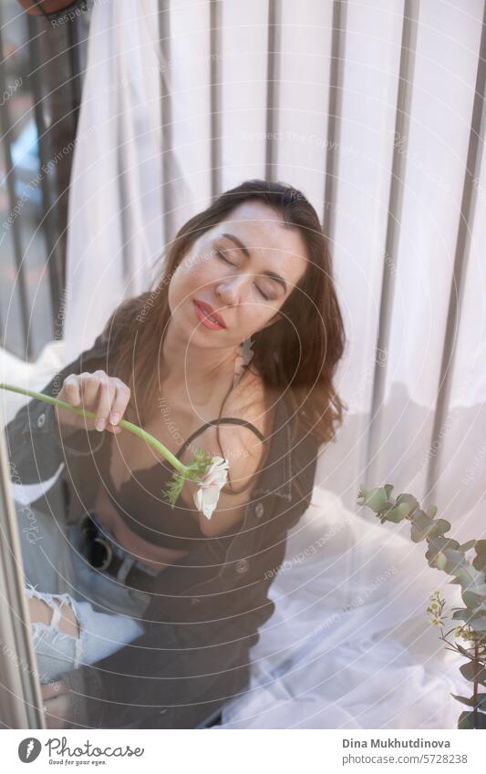 schöne Frau in Grunge-Outfit mit weißer Blume sitzt auf dem Balkon der Wohnung 25 bis 30 Jahre Junge Frau Grunge-Look Bekleidung Outfits Sitzen Stil Mode
