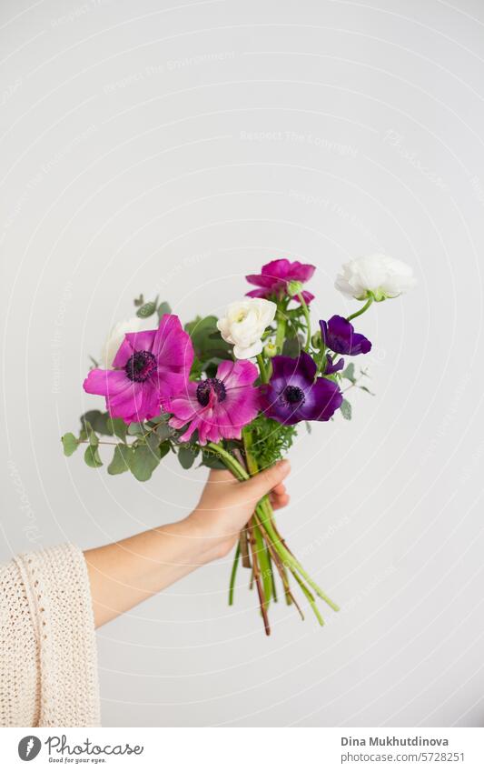 Hand einer Frau, die einen Blumenstrauß auf weißem Hintergrund hält. Ich kann mir Blumen kaufen. Alles Gute zum Geburtstag oder Jahrestag. geblümt Blumenhändler