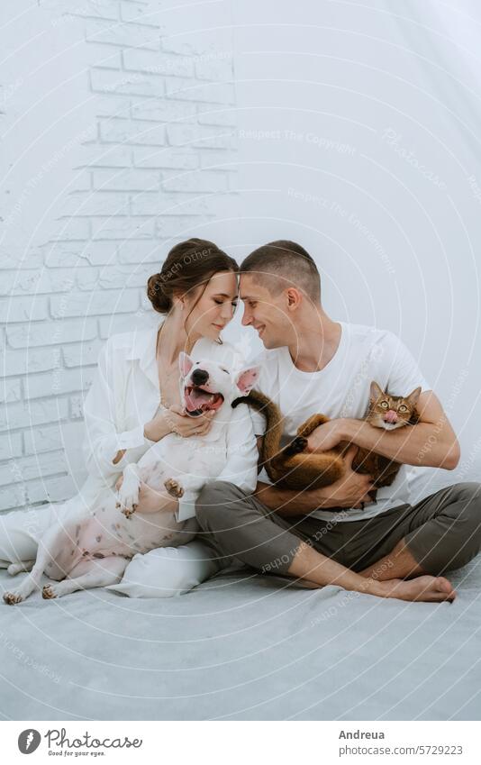 Junges Paar Mann und Frau in einem hellen Raum spielen mit Haustieren weiß Hund sanft Wolle Licht Baustein Wand Eckstoß grau Fliesen u. Kacheln Leitwerke Freund