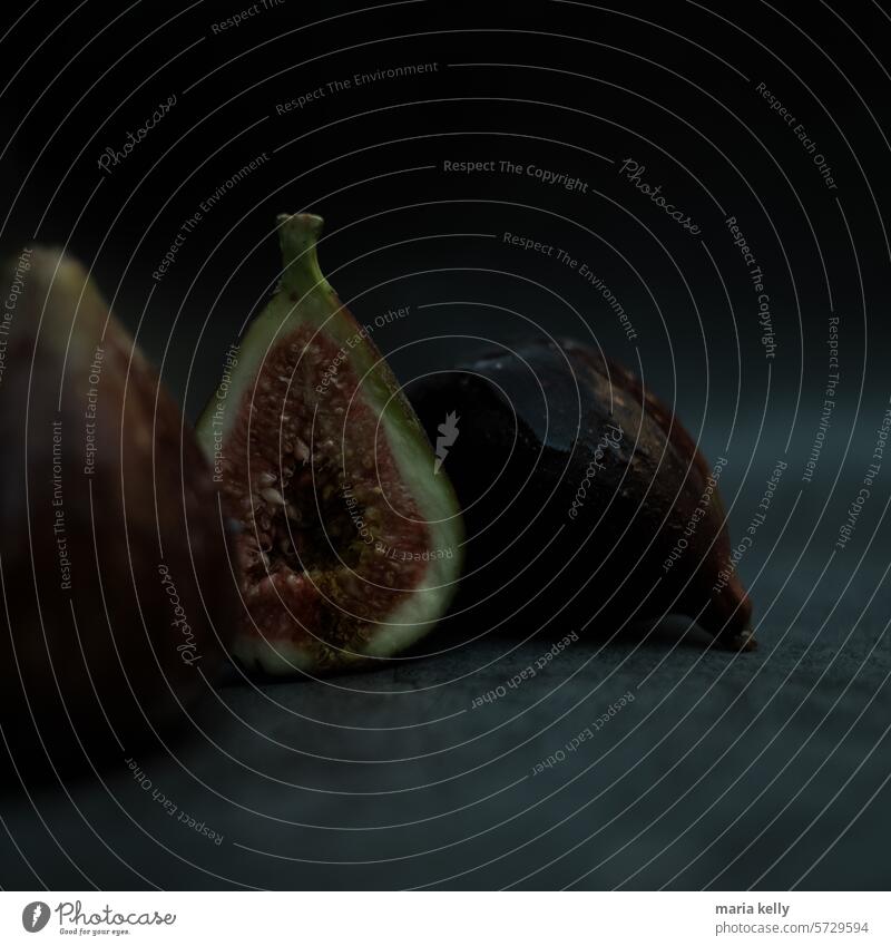 Das Bild zeigt ein paar Feigen auf einer schwarzen Fläche. purpur Frucht Früchte Samen rot grün Birne Form
