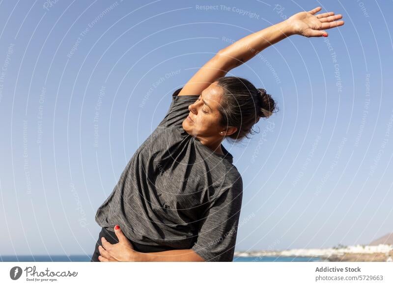 Frau dehnt sich am Strand bei einem Fitnessstudio im Freien strecken Übung MEER Gesundheit aktiv Lifestyle seitliche Dehnung Wellness Training tagsüber Himmel