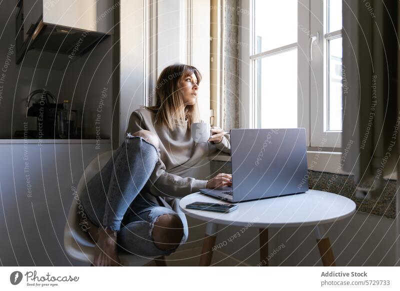 Frau entspannt sich mit Kaffee bei der Arbeit am Laptop zu Hause heimwärts entspannend natürliches Licht Fenster gemütlich Sitzen arbeiten Tasse