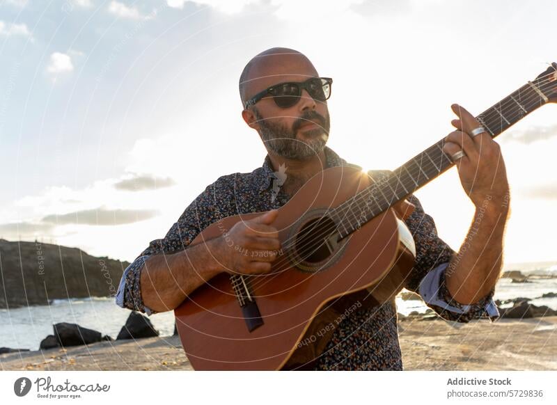 Mann spielt Gitarre am Meer bei Sonnenuntergang männlich akustisch Spielen Musiker Strand MEER Instrument Wellen zusammenbrechend Hintergrund Atmosphäre
