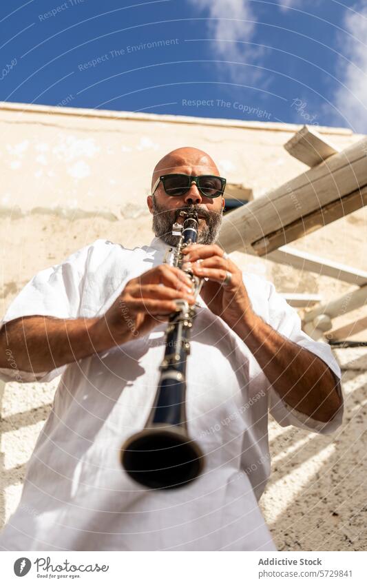 Bärtiger Mann spielt Klarinette im Freien an einem sonnigen Tag männlich Musiker Vollbart Sonnenbrille Blauer Himmel Leistung Jazz internationaler Tag Kultur