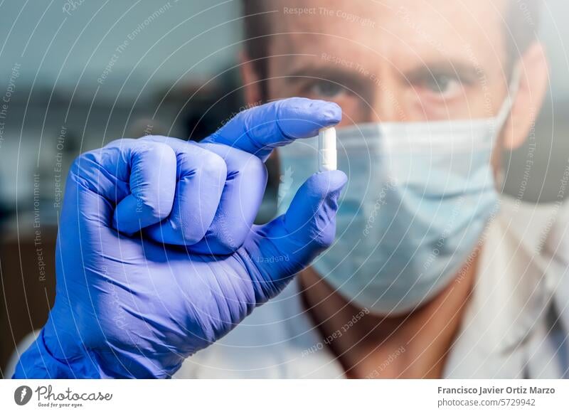 Wissenschaftlerin mit medizinischer Maske zeigt weiße Pille. Forschungskonzept. Selektiver Fokus. Tablette Labor Medizin forschen Arzt Apotheke Person