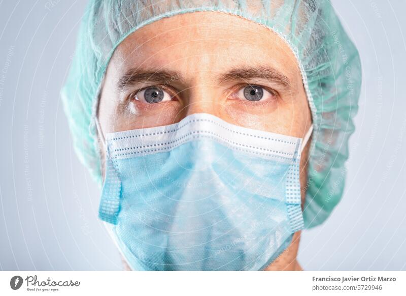 Nahaufnahme eines Arztes mit blauen Augen, die durch Maske und Kappe geschützt sind. Selektiver Fokus. Medizin Wissenschaftler Mann Gesichtsmaske Biotechnologie