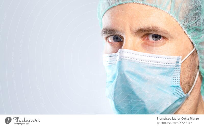Nahaufnahme eines Arztes mit blauen Augen, die durch Maske und Kappe geschützt sind. Selektiver Fokus. Medizin Wissenschaftler Mann Gesichtsmaske