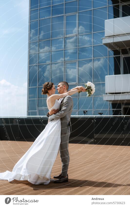erstes Treffen von Braut und Bräutigam auf dem Dach eines Wolkenkratzers blau Blumenstrauß Großstadt Paar Tag Kleid für immer striegeln Fröhlichkeit Freude