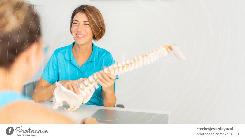 Eine Physiotherapeutin erklärt ihrem Patienten anhand eines anatomischen Skeletts das Problem der Schmerzen im unteren Rücken und der Einklemmung der Wirbel
