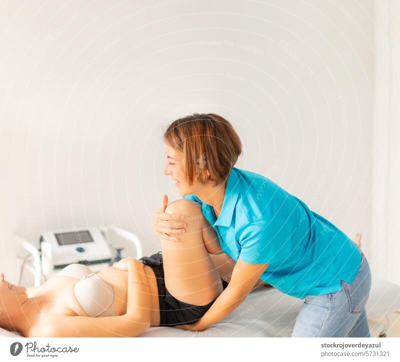 Eine Physiotherapeutin führt Dehnungen und Massagen an den Beinen und Hüften ihrer Patientin durch Klinik Rehabilitation geduldig Gesundheitswesen