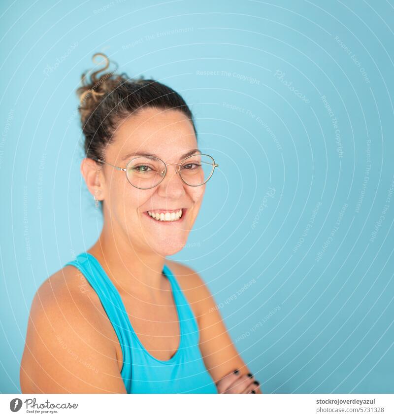 Eine Brillenträgerin lächelt glücklich und selbstbewusst nach einer manuellen Therapie in einer Physiotherapieklinik Frau Porträt jung Person Haare aufstellen