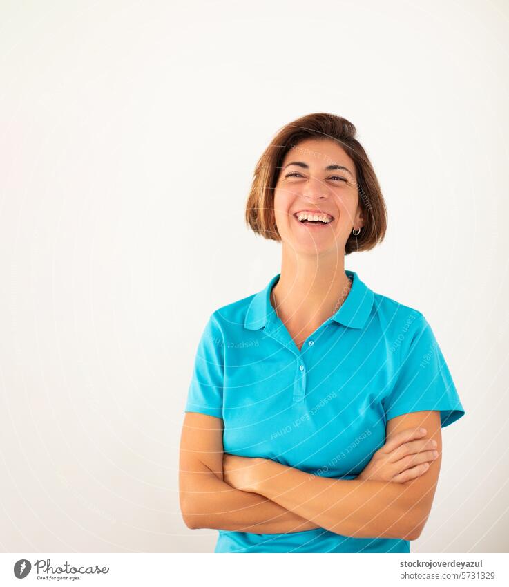 Eine Frau, Inhaberin einer eigenen Physiotherapiepraxis, lächelt selbstbewusst auf einem schlichten weißen Hintergrund. Physiotherapeutin Frauen Erwachsener