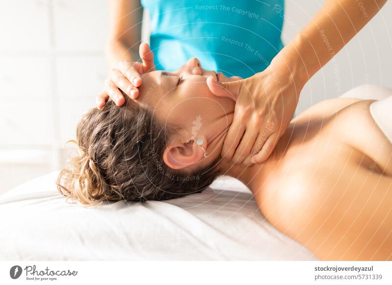 Eine Physiotherapeutin führt eine entspannende und entkrampfende Massage am Nacken ihrer Patientin durch, um sie von Schmerzen und Verspannungen zu befreien