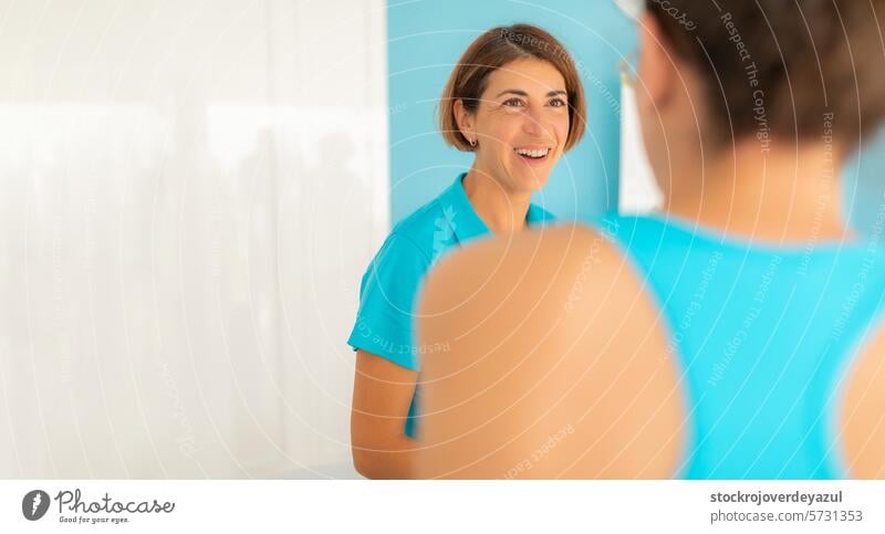 Eine Frau, eine Physiotherapeutin, lächelt, während sie sich angeregt mit einem ihrer Patienten in der Klinik unterhält Rehabilitation geduldig Physiotherapie