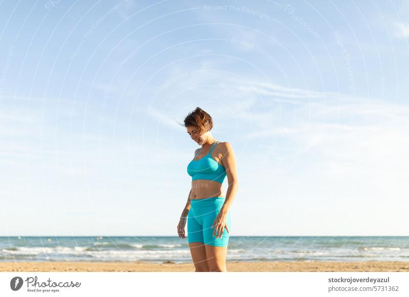 Eine Frau ruht sich nach Pilates-Übungen am Strand mit Blick auf das Meer aus Yoga mediterran Spanien Körper-Geist-Übung Kontrolleogie Sonnenuntergang