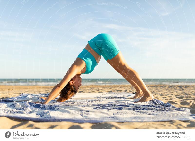 Eine Frau mittleren Alters macht Pilates-Übungen am Strand, um fit zu bleiben Yoga mediterran Spanien Körper-Geist-Übung Kontrolleogie Sonnenuntergang Sport