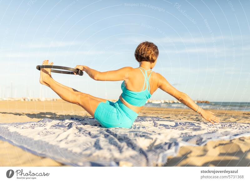Eine Frau macht Pilates-Übungen mit einem Pilates-Ring am Strand, um fit zu bleiben Yoga mediterran Spanien Körper-Geist-Übung Sonnenuntergang MEER Sport Sommer