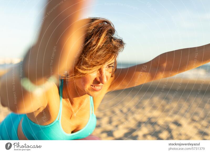 Eine Frau macht Übungen und Pilates-Bewegungen am Strand, um fit zu bleiben Yoga mediterran Spanien Körper-Geist-Übung Kontrolleogie Sonnenuntergang Fitness