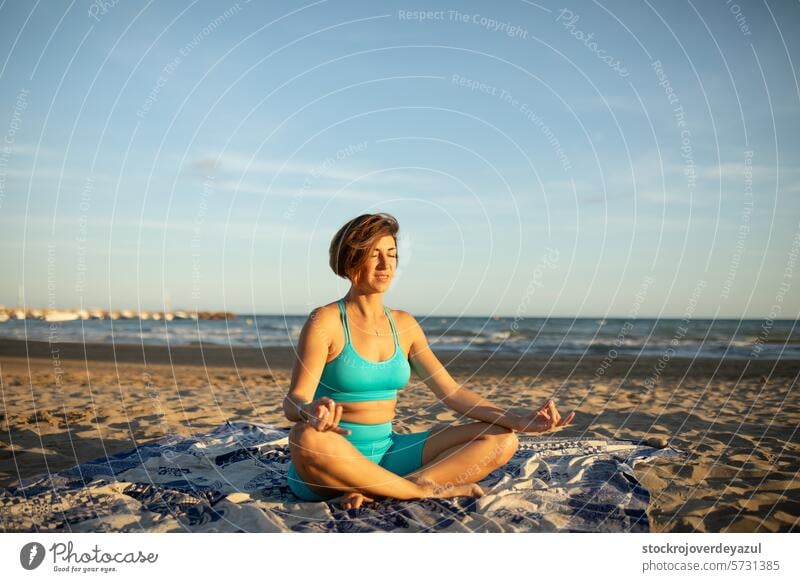 Eine Frau macht Meditationsübungen am Strand, nach einer Pilates-Sitzung bei Sonnenuntergang Yoga mediterran Spanien meditierend MEER Natur Sommer Erholung Pose