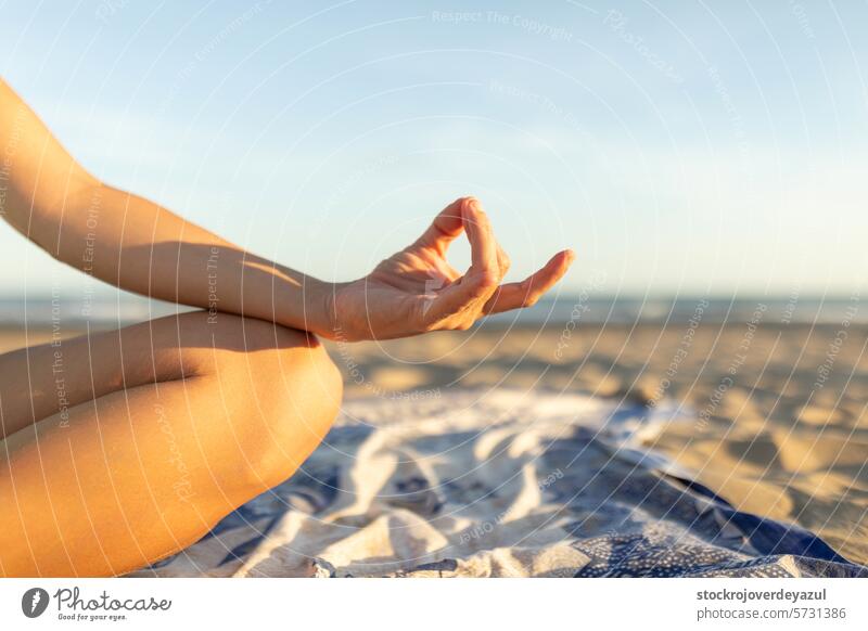 Die Hand einer Frau, die am Strand nach einer Pilates-Sitzung bei Sonnenuntergang Meditationsübungen durchführt Yoga mediterran Spanien Körper-Geist-Übung