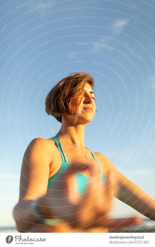 Eine Frau macht Meditationsübungen am Strand, nach einer Pilates-Sitzung bei Sonnenuntergang Yoga mediterran Spanien Person Lifestyle Gesundheit jung Training